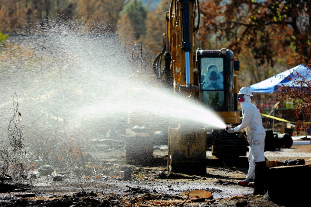 Hazmat teams spray fire sites to mitigate airborne toxic chemicals during debris removal after the Valley Fire in Middletown, California
