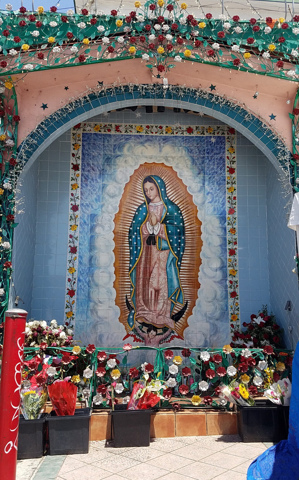 Shrine of the Virgin of Guadalupe surrounded by ceramic flowers.