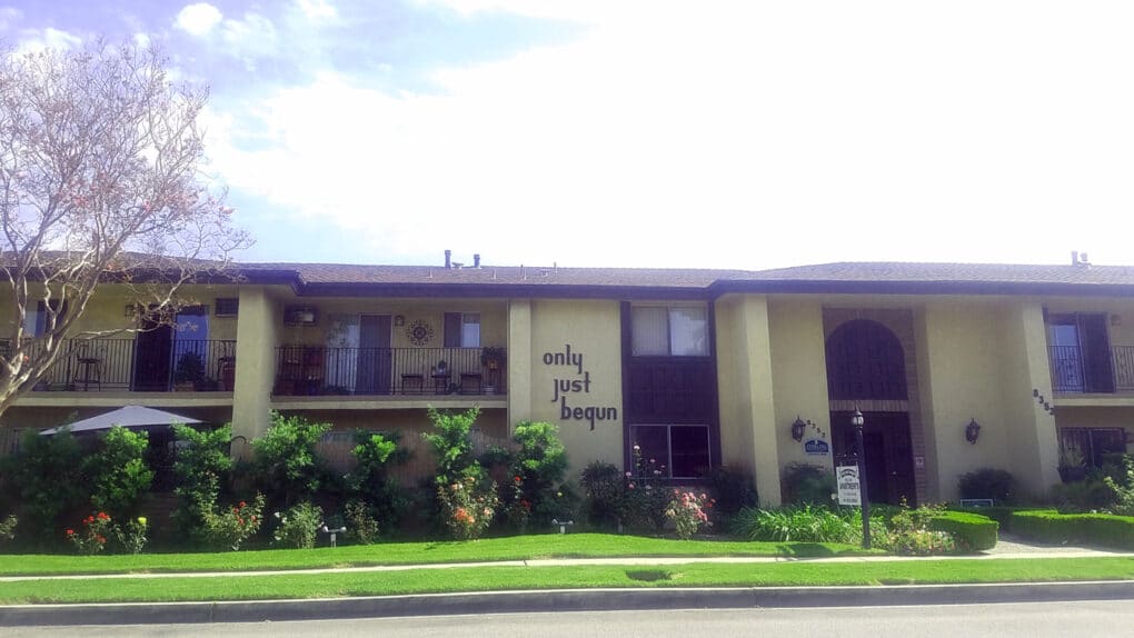 Two story apartment building with lawn and tres.
