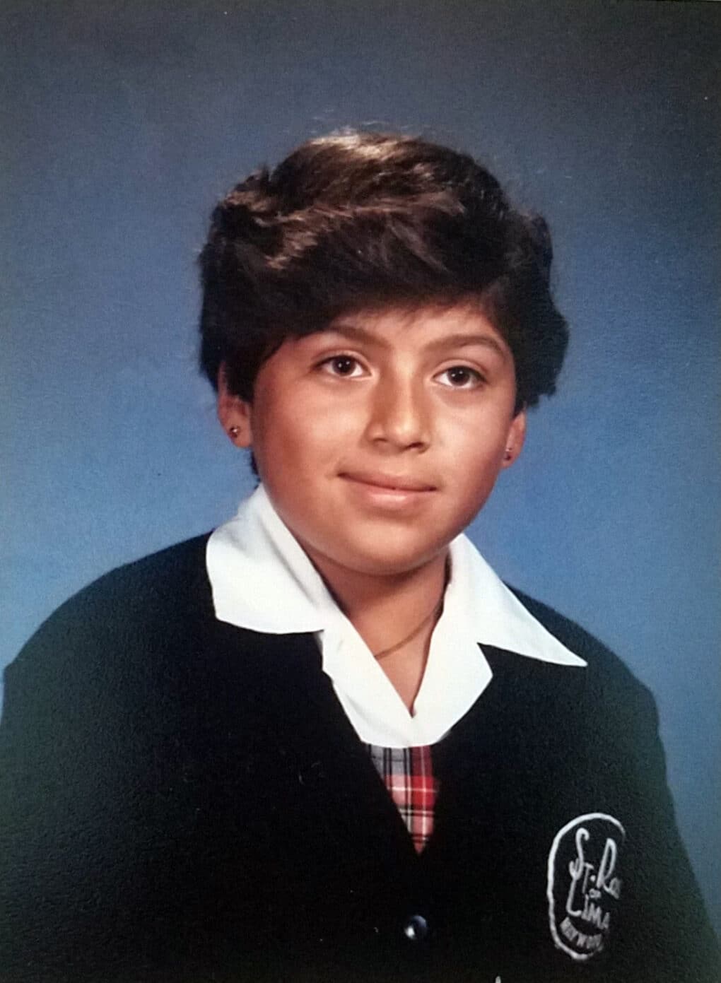 School picture of girl with short hair in Catholic school uniform.