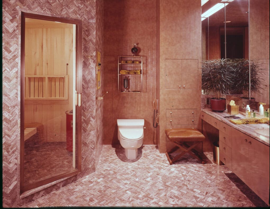 Elaborately tiled bathroom, with wood-paneled sauna behind glass door.