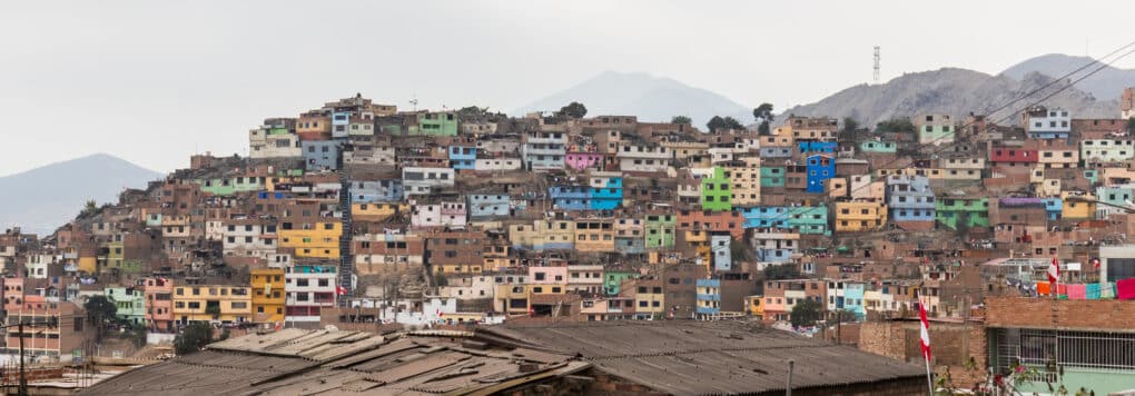 Densely built hillside neighborhood of small colorful houses, with mountains in the background.