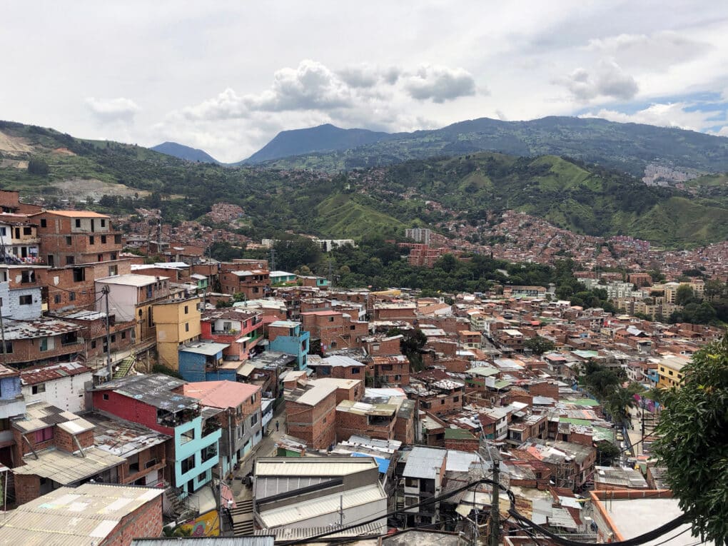 Hilly neighborhood with mountains in the background, densely built with small colorful houses in the foreground.