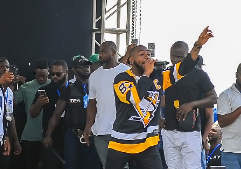 Click to Enlarge Davido performing on stage, with his hand up in the air.