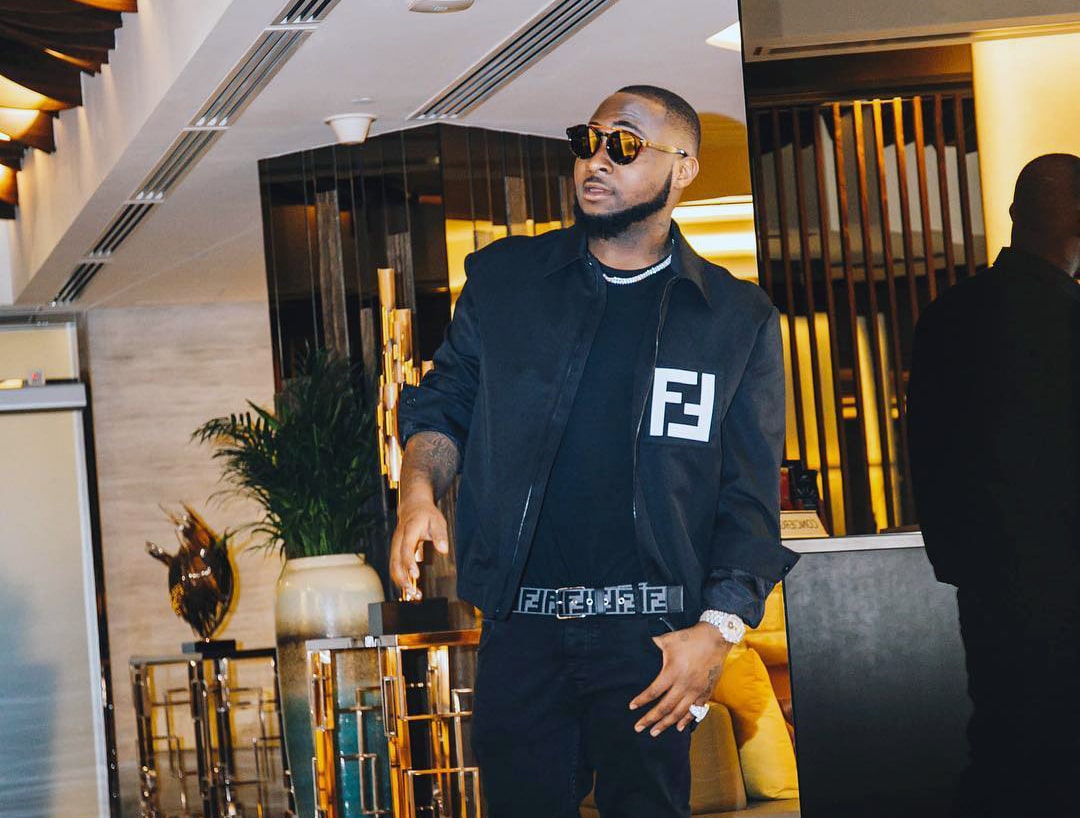 Click to Enlarge Davido walking and wearing Black bomber jacket.