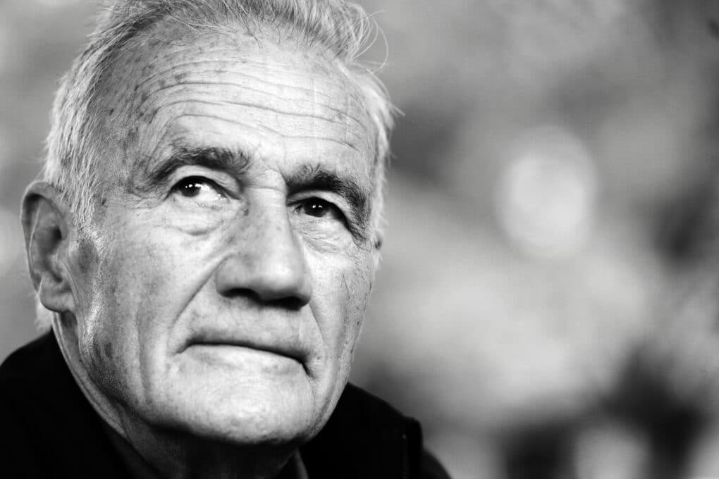 Close-up black-and-white portrait of aging white man, looking up and to the left beyond the frame.