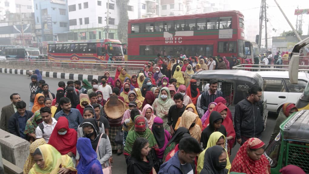 Color photograph of large crowd of women in colorful saris and veils disembarking from a double-decker bus.