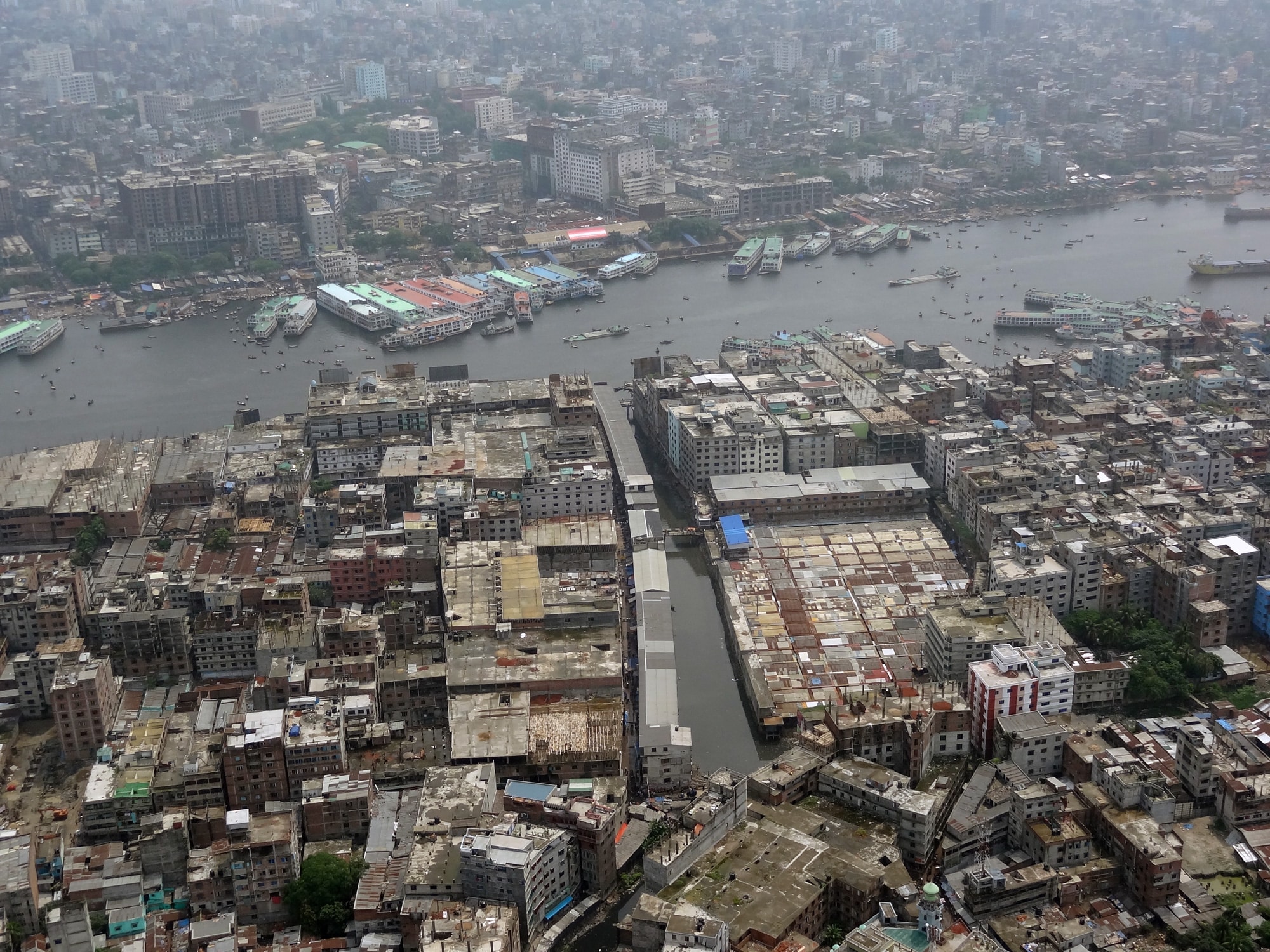 Click to Enlarge Color photo from an elevated perspective showing densely built city with canal running perpendicular to a large and busily trafficked river.