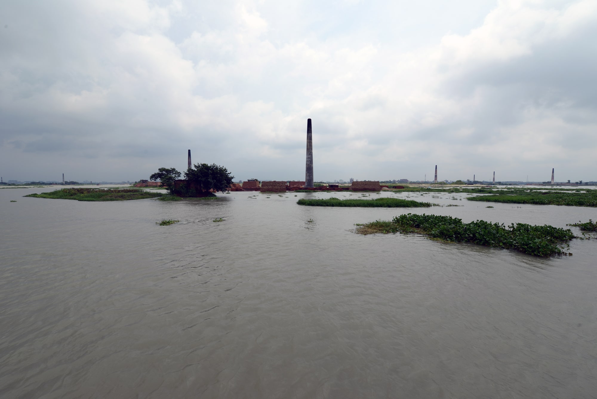Click to Enlarge Expanse of water from which arise hummocks of greenery and a series of pillars.