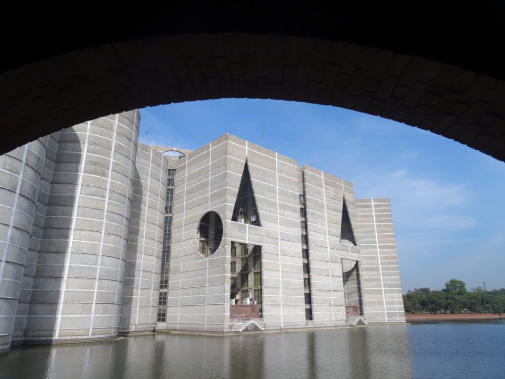 Color photograph of geometric concrete building set in a reflecting pool.