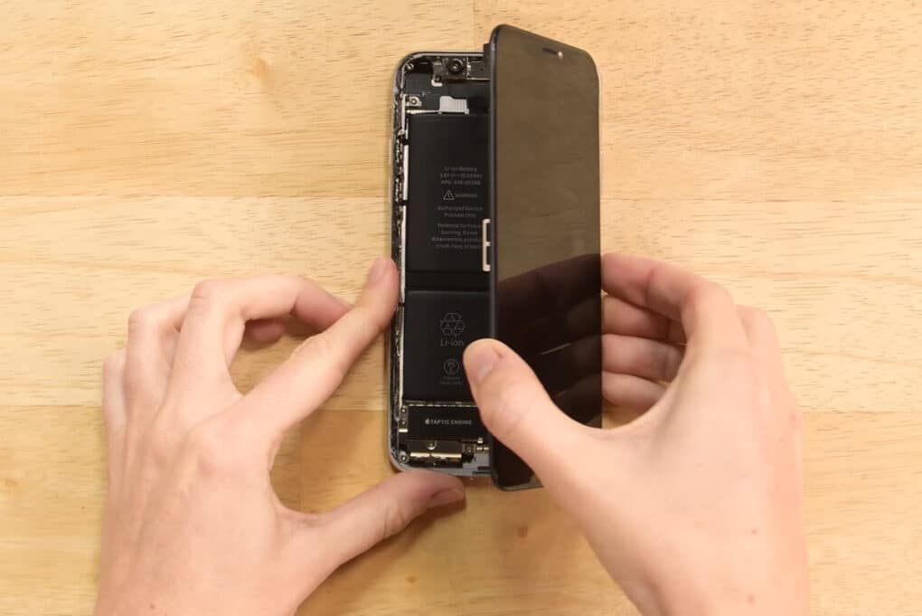 Overhead photo of an iphone on a table, being opened by two hands.