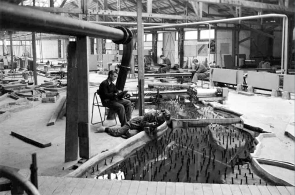 Workers inside a warehouse, adjusting components of a large hydraulic model