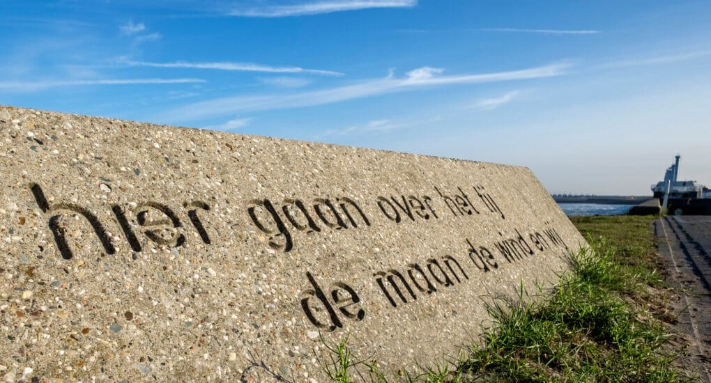 Stone monument inscribed with a Dutch phrase that reads, in translation, “Here the tide is ruled by the wind, the moon, and us.”