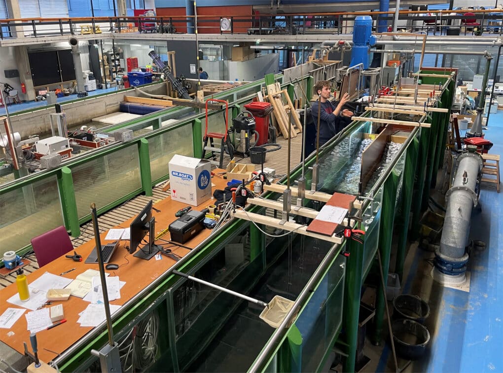 Man working with a hydraulic model in a laboratory setting surrounded by other machines and models.