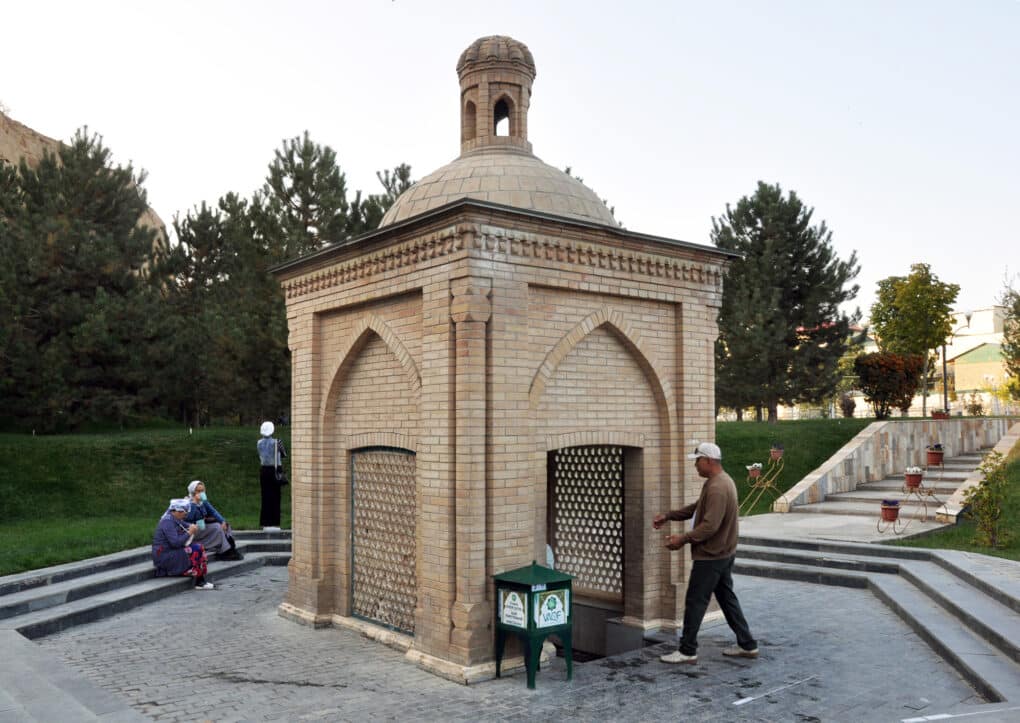 Color photograph of man entering a small brick pavilion.