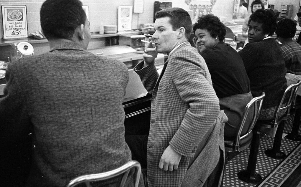 Black-and-white photograph of well-dressed Black and white patrons seated at a lunch counter.