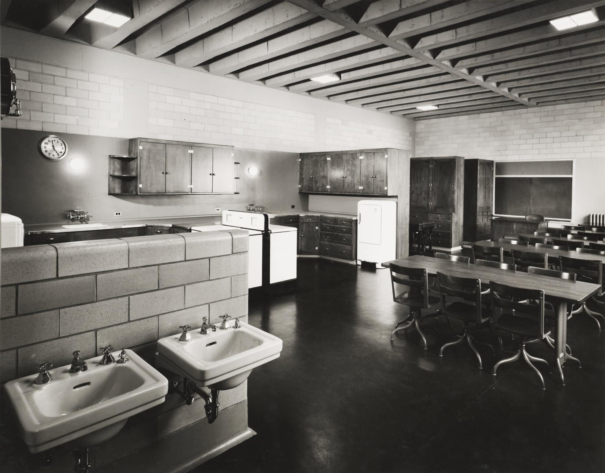 Click to Enlarge Classroom with tables, sinks, several stoves, cupboards, and a refrigerator. There are no students present.
