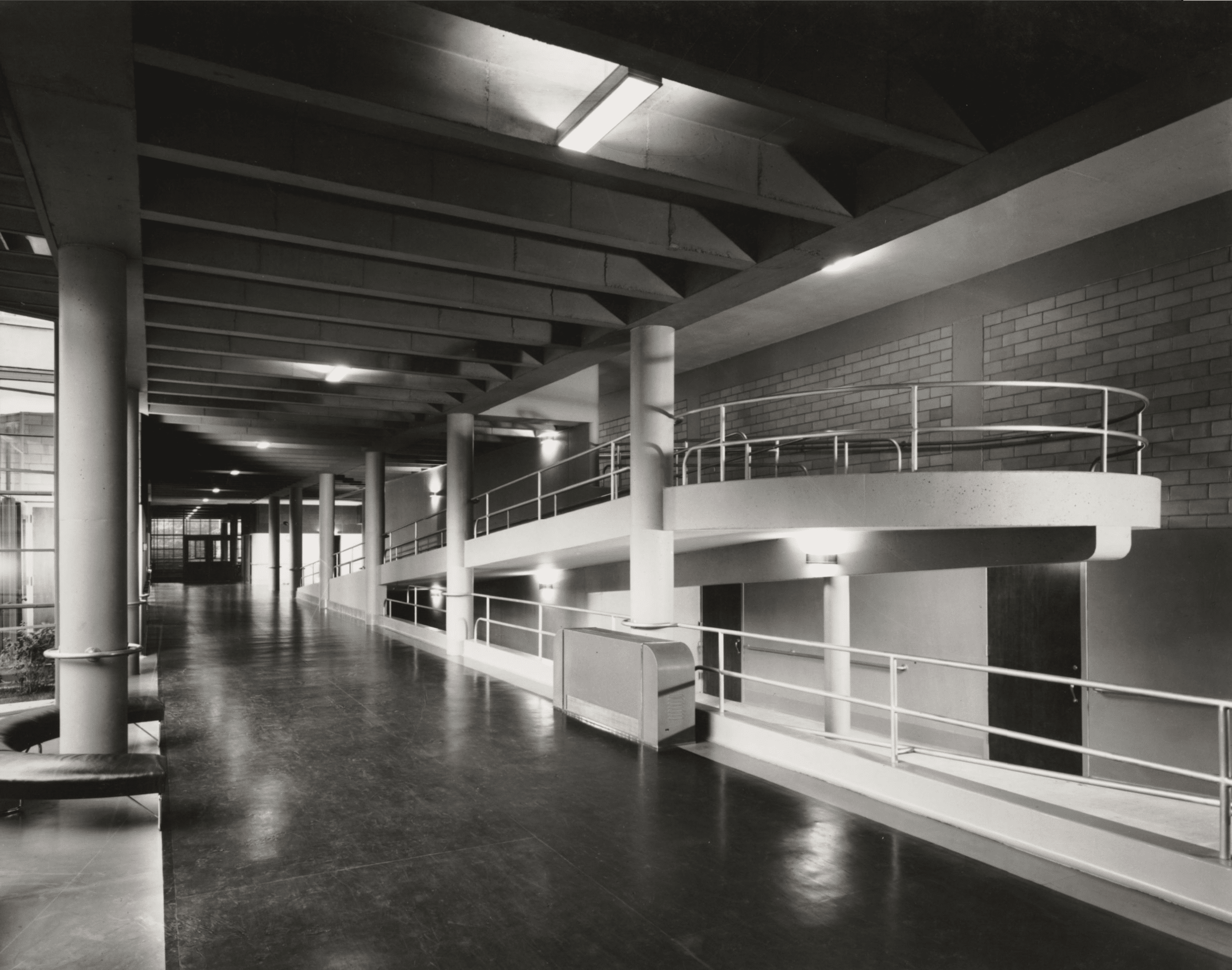 Click to Enlarge Hallway of school with glass atrium on left and wide ramp on ramp. Photographic documentation of architecture — no students are present.