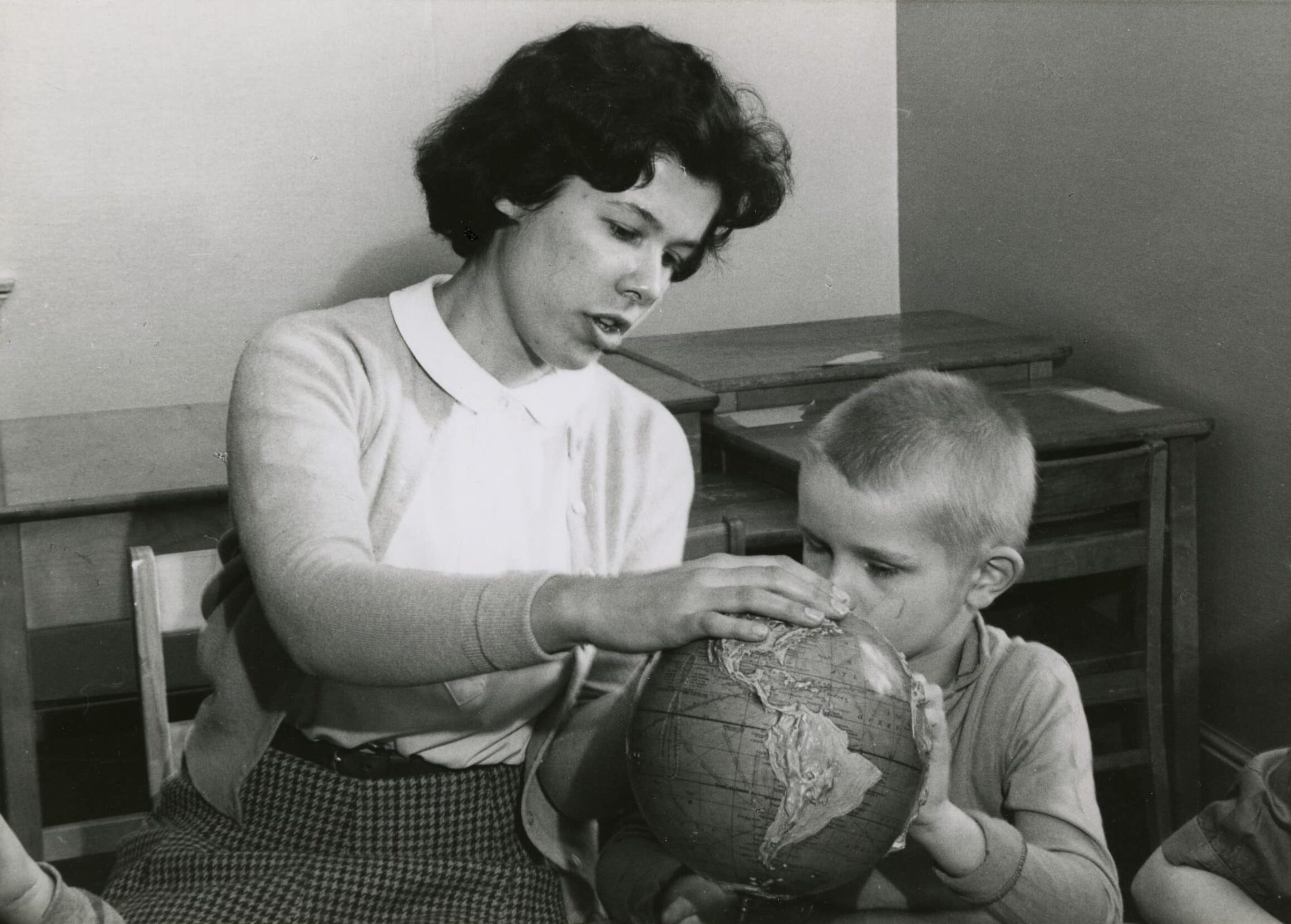 Click to Enlarge A teacher or aide with a young boy, both exploring a tactile globe.