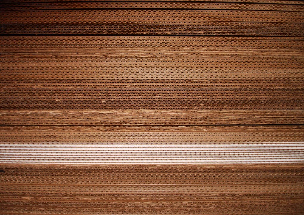 An abstract view of many dozens or hundreds of corrugated cardboard sheets stacked on top of one another.