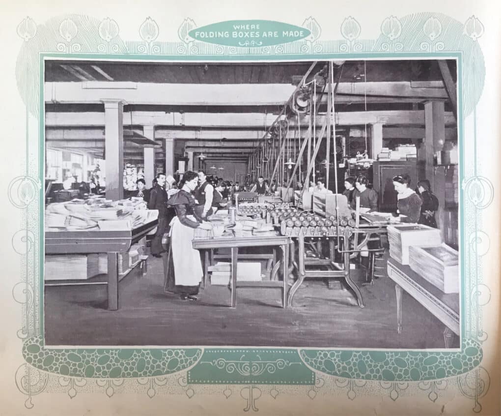 A black and white photo of workers, mostly women, in an industrial setting. The title says "Where Folding Boxes Are Made."