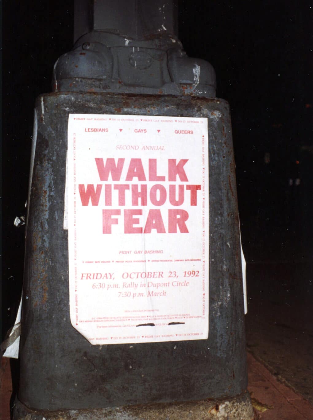 Color photograph of poster (red letters on white ground) on lower portion of streetlight stanchion.