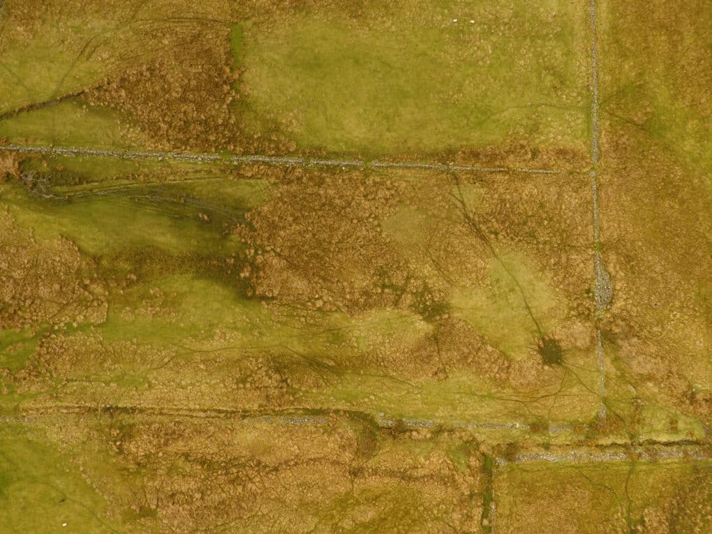 Drone photograph showing grassy fields bordered by straight fence lines.