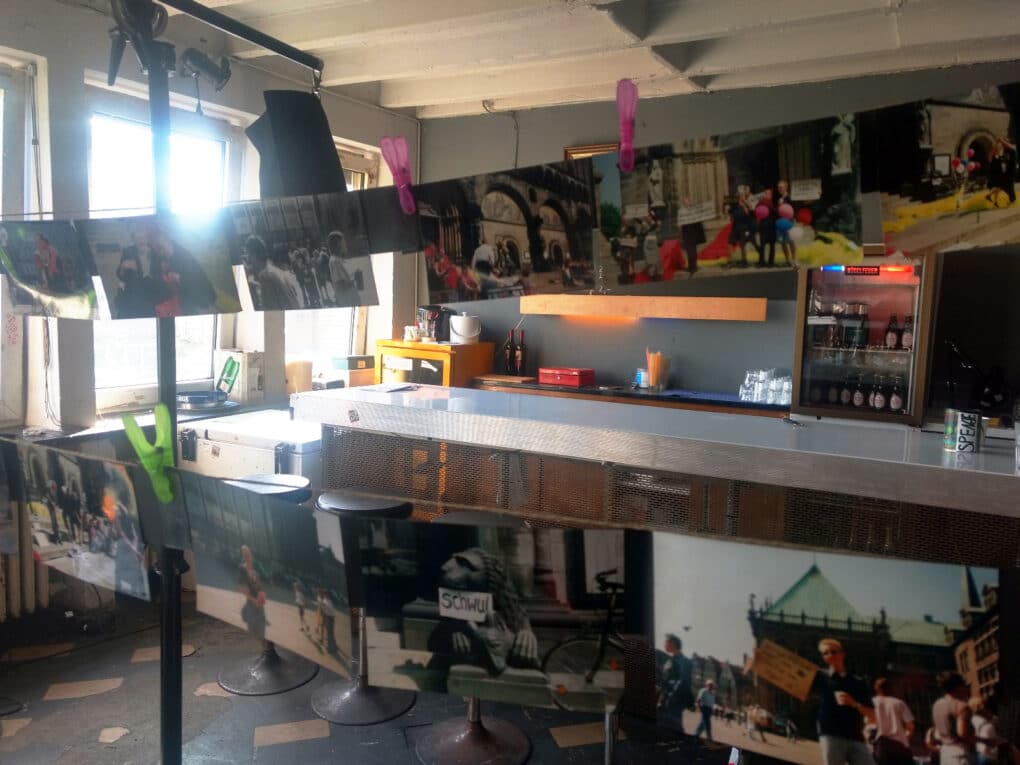 A series of color photos hang on a clothesline in a workroom.