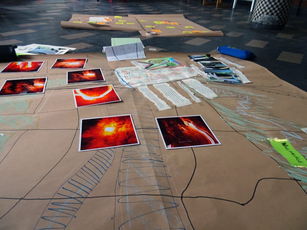 Two hand-drawn maps on large sheets of brown paper, showing lines, symbols, labels and stickers. Each maps includes different styles and shapes of mark and image.