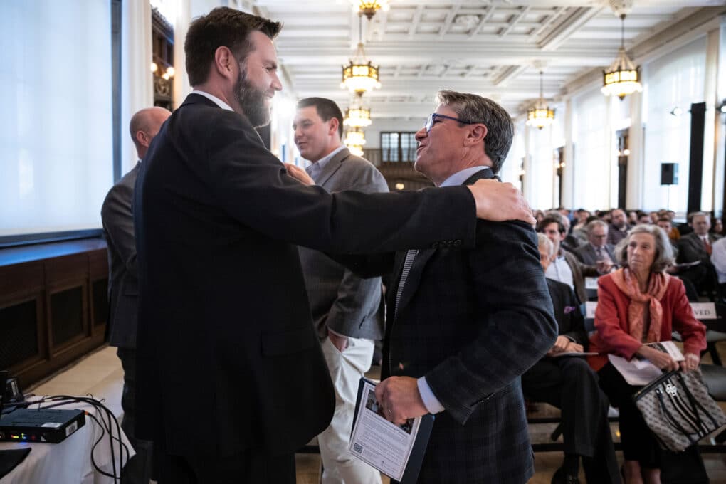 Color photograph of two white men, both in suits, embracing.