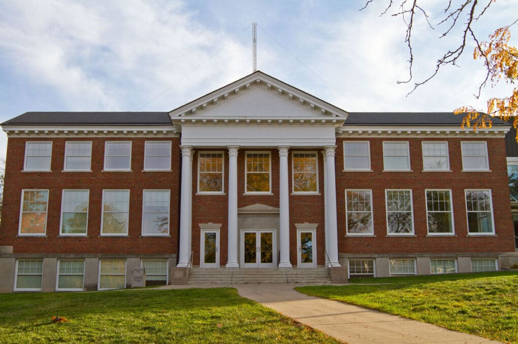 Red brick college building with simple white classical portico.