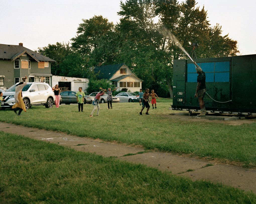 LaToya Ruby Frazier, Shea Cobb, Amber Hasan, and Her Children, Nieces, and Nephews (Zari, DJ, Jayda, Justin, Justace, Jaylen) and Their Friends Playing in the Water Moses West Is Spraying from His Atmospheric Water Generator on North Saginaw Street Between East Marengo Avenue and East Pulaski Avenue, Flint, Michigan, 2019. 