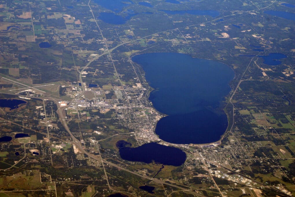 Color aerial photograph of small town with large and small lakes at its center.