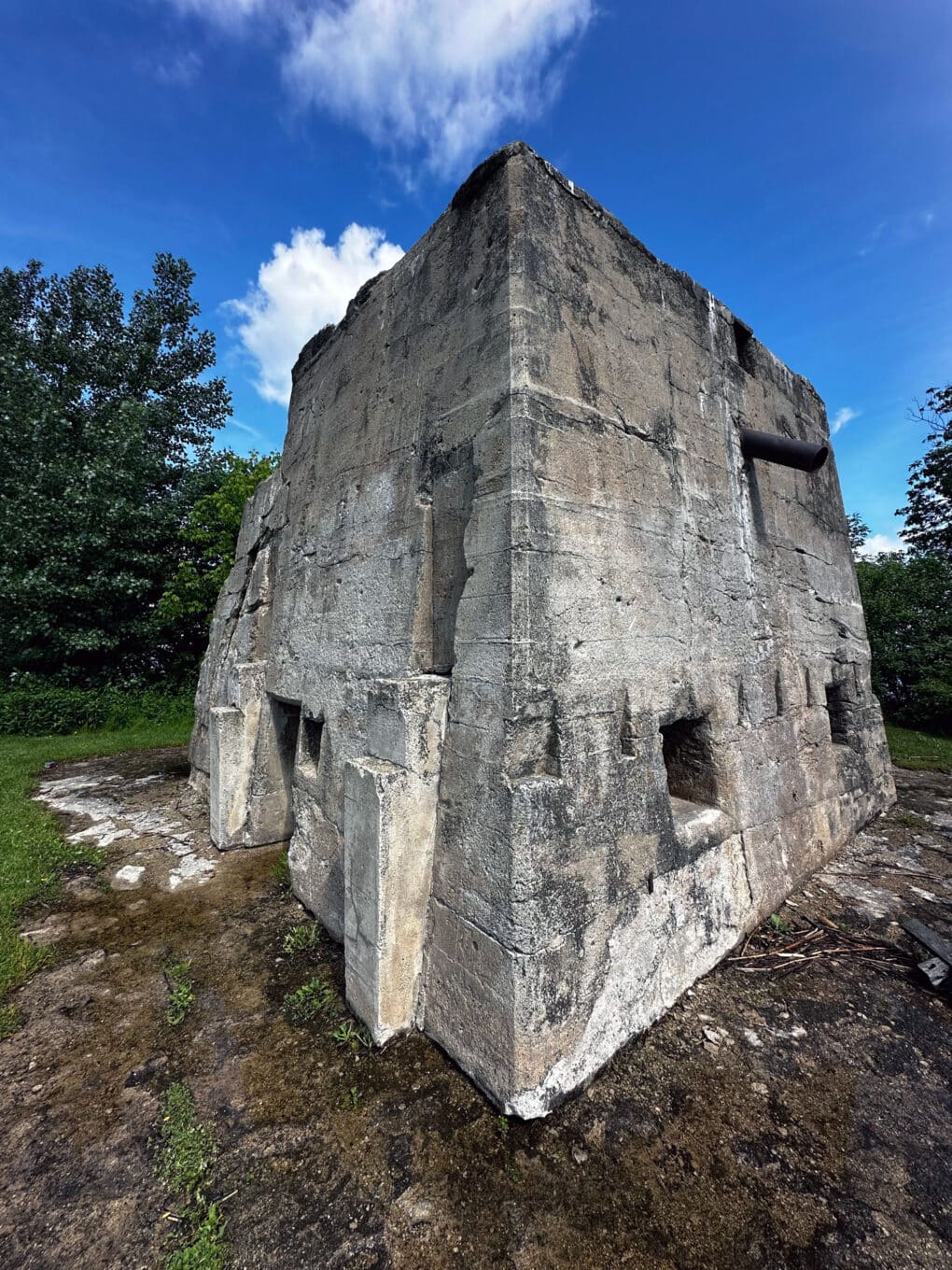 Color photograph of large concrete pillar with various inset niches, against bright blue sky.
