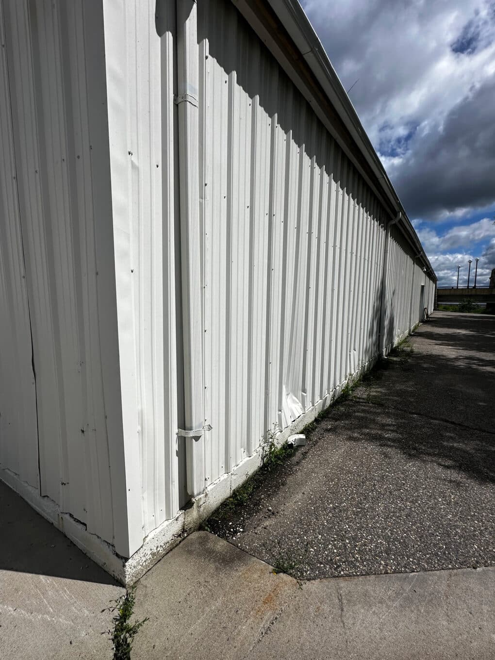 Color photograph of large nondescript white-painted corrugated storage shed.