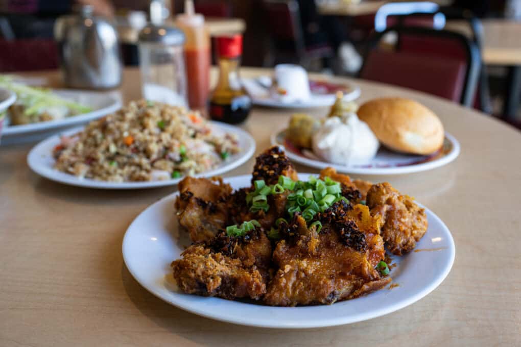 A plate of fried pork chops with scallions on top. 