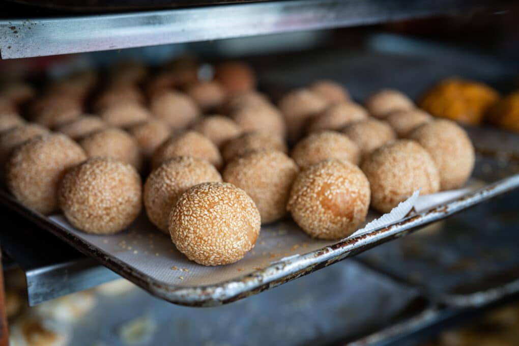 Sheet pan full of round sesame balls.