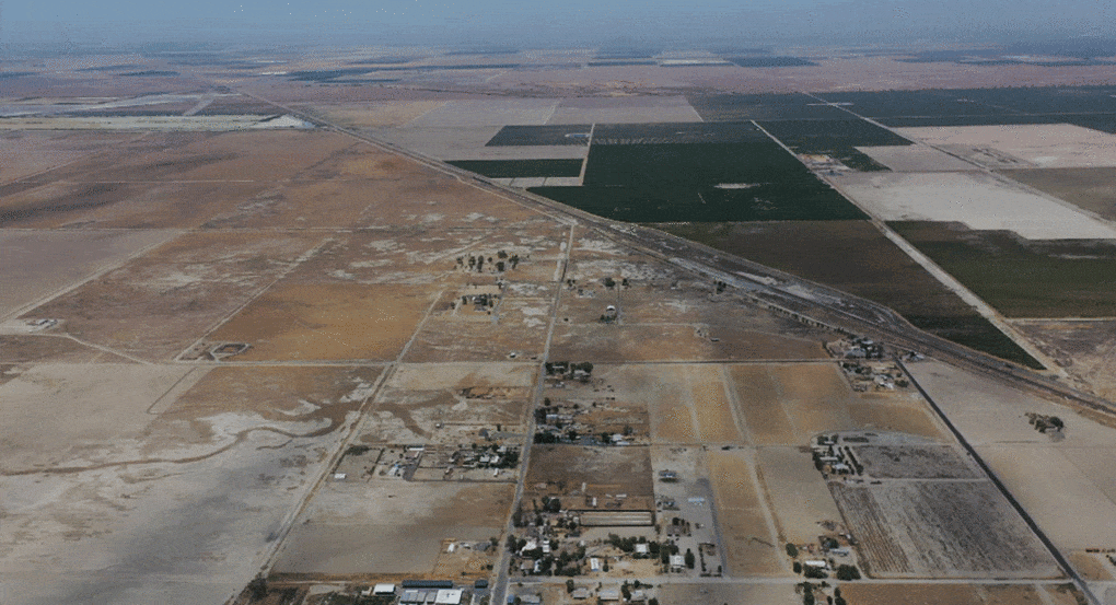 Drone image of a portion of Allensworth (foreground) looking north at its context of pistachio fields and fallowed land due to extreme drought, July 2022 (drone operated by Yuliang Jiang).
