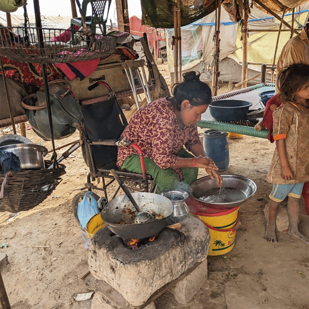 In a tent settlement in Karachi, a woman cooks lunch on a clay stove using wood and plastic wrappers for fuel. 