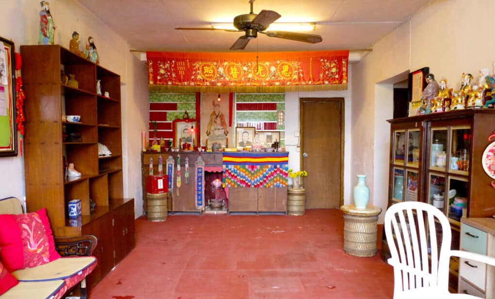 Photo of large room with altar, shelves of Buddhist statues, and colorful hangings.