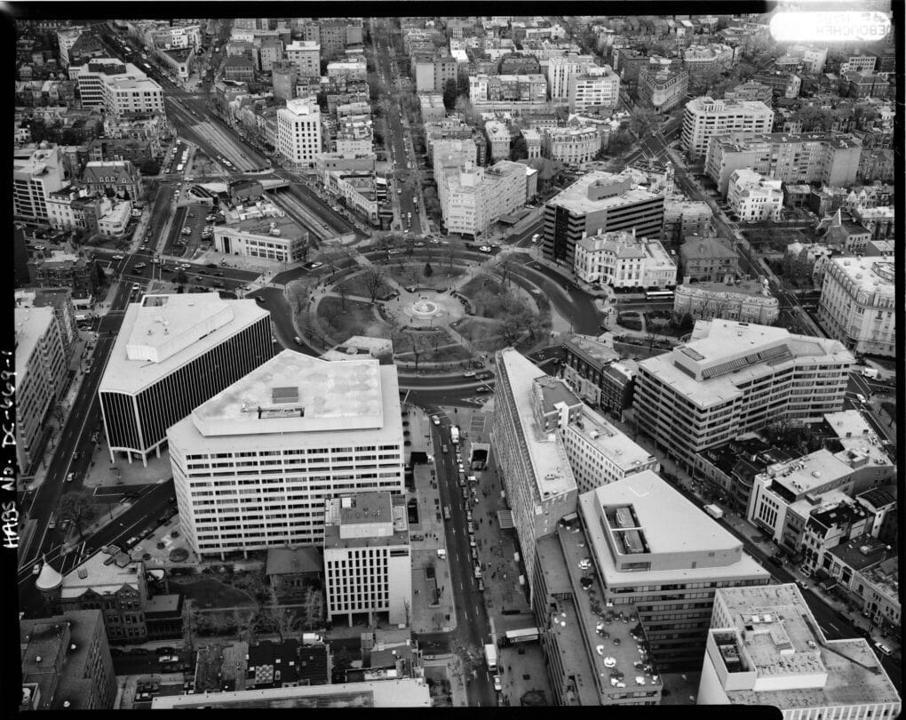 Black-and-white aerial photograph of large circular park in built-up city.