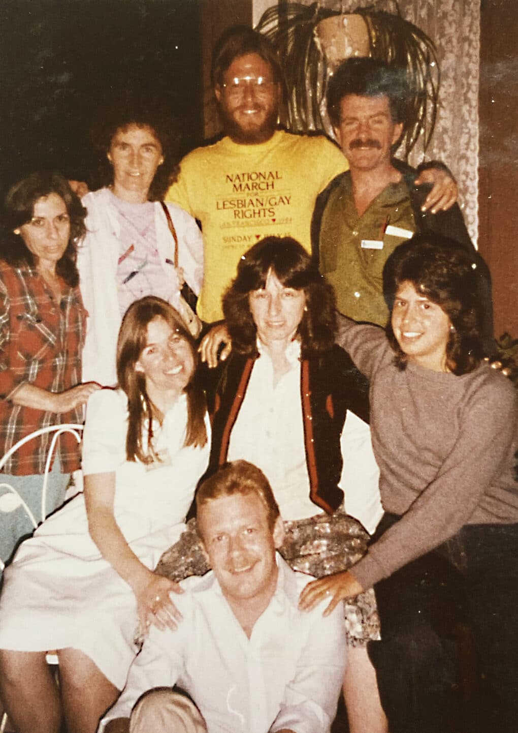 Eight people in a color group photo, all smiling; five appear to be women, and three appear to be men. 