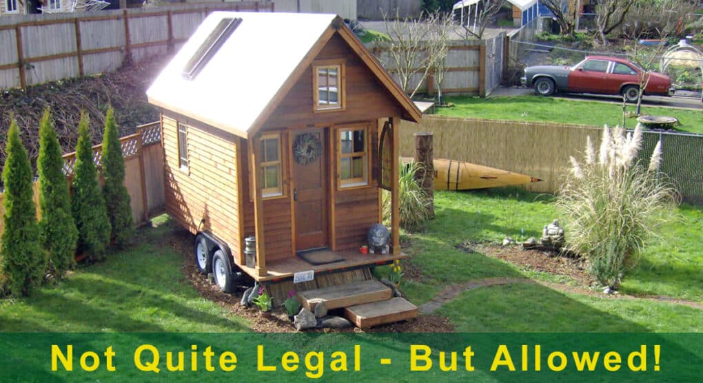 Color photograph of tiny home parked in a suburban yard, with added overlaid caption reading "Not Quite Legal - But Allowed!"
