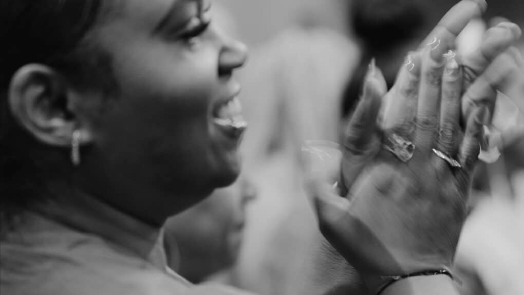 Black-and-white photograph of a black woman smiling and clapping.