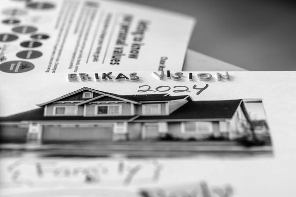 Black-and-white photograph of a picture of a split-level house, captioned with decal letters "ERIKAS VISION 2024"