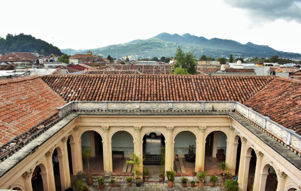 Color photograph of columned courtyard seen from above, with green mountain peak in the distance.