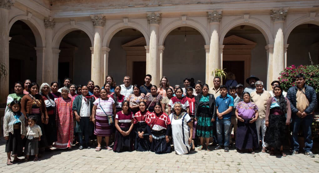 Color photograph of large group of people assembled in a colonnaded courtyard.