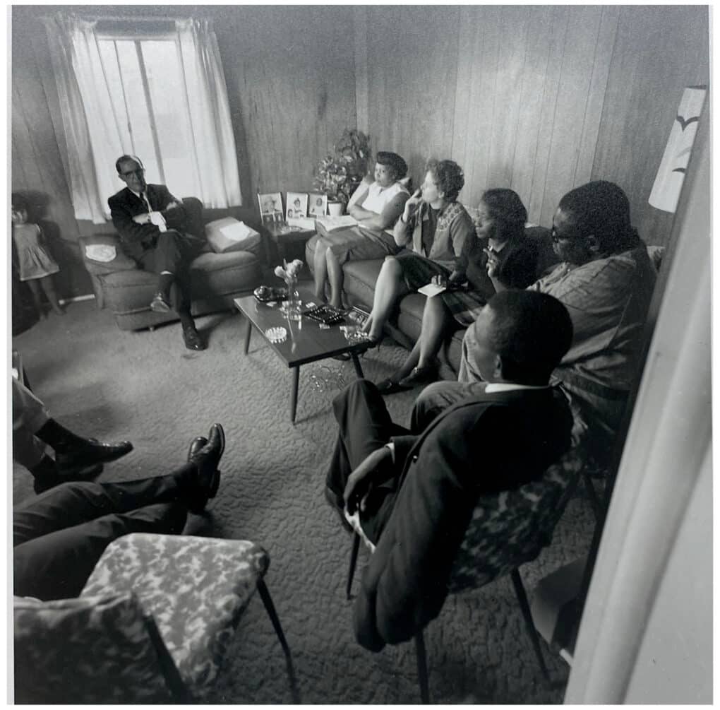 Black-and-white photograph of eight people, Black and White, seated in a living room.