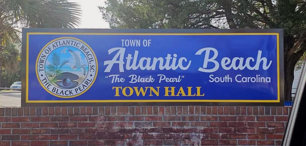 Color photograph oof blue sign reading "Town of Atlantic Beach, South Carolina, "The Black Pearl," Town Hall"