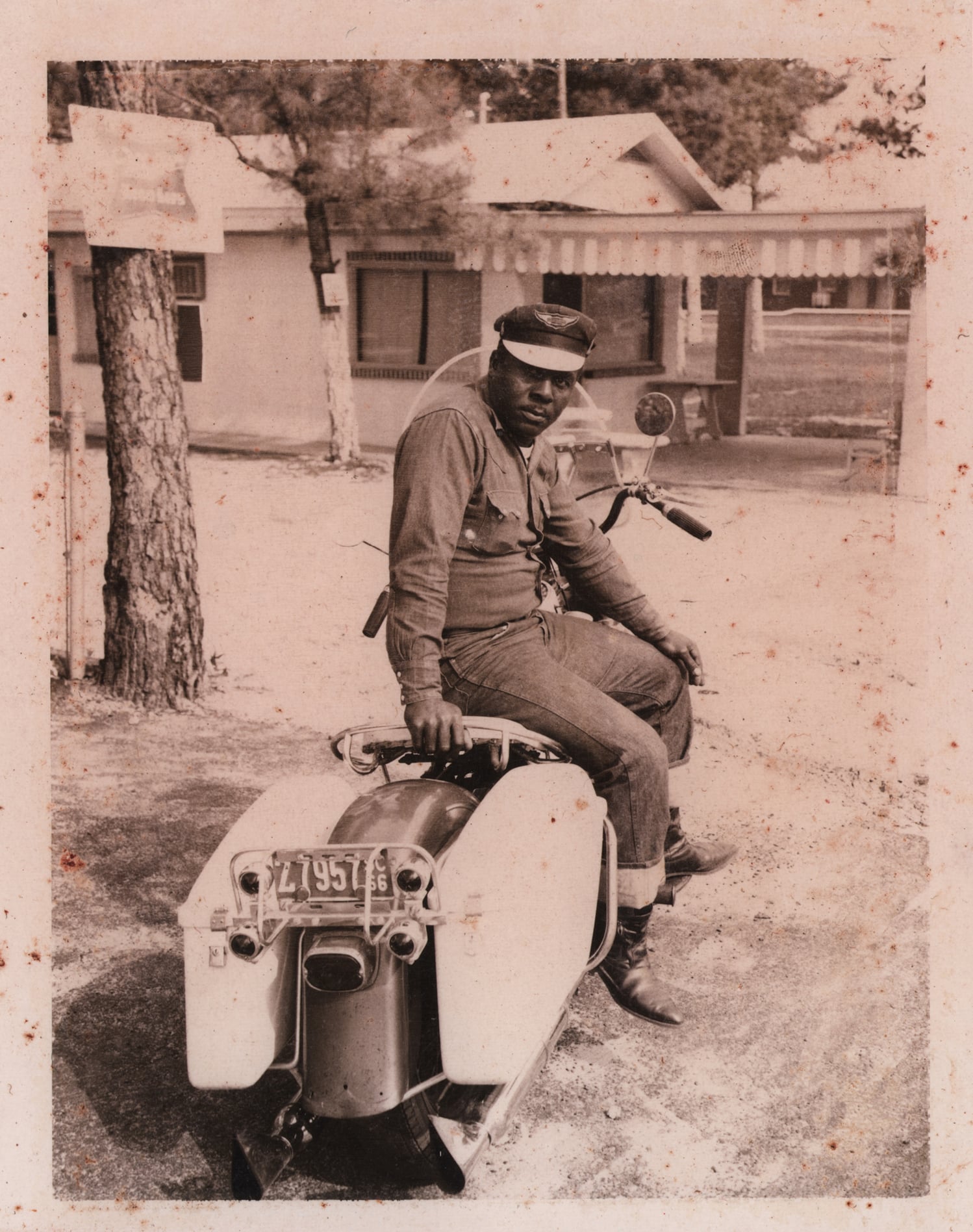Click to Enlarge Black-and-white photograph of Black man seated on a motorcycle.